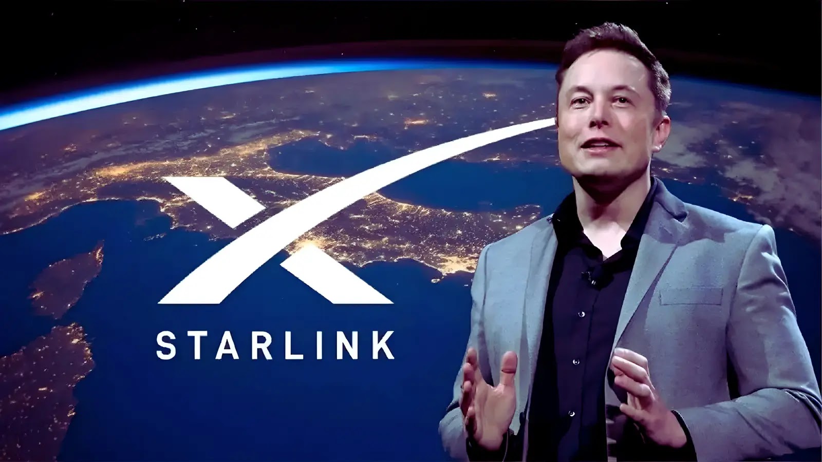 A man in a suit stands in front of a large Starlink logo with an image of Earth from space as the background, showing illuminated continents at night.
