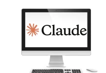 A computer monitor displays the word Claude next to an orange starburst logo on a white background. A wireless mouse is visible beside the monitor.