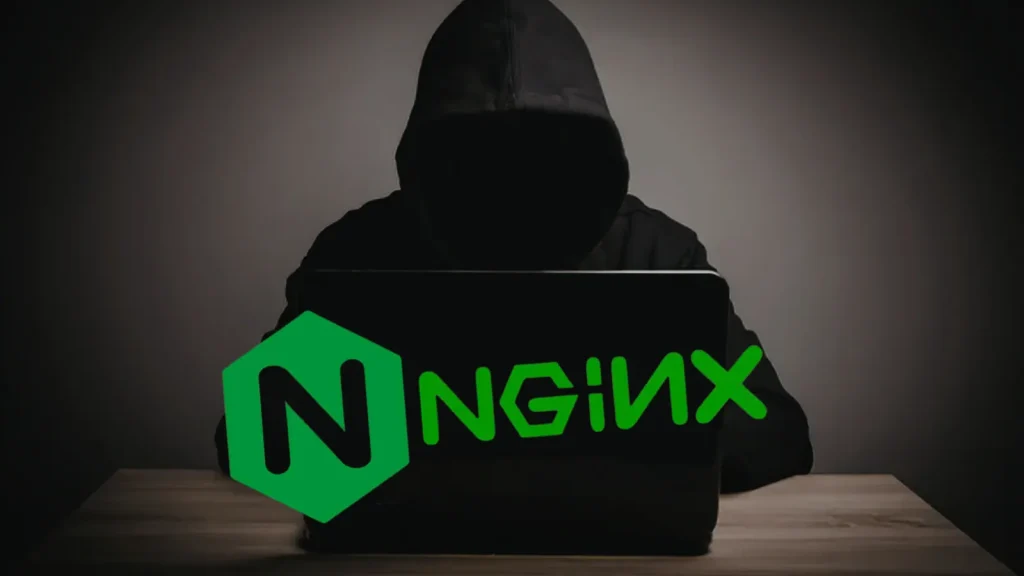 A person in a dark hoodie sits at a desk with a laptop, face obscured in shadow. The NGINX logo is prominently displayed on the laptop screen. The background is dimly lit.